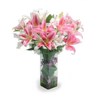 Glass vase arrangement of 10 Asiatic Lilies with green leaves.